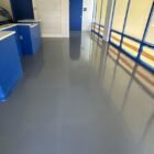 Piso epóxico gris brillante en un local comercial, fácil de limpiar piso epóxico con trapeador y detergente suave